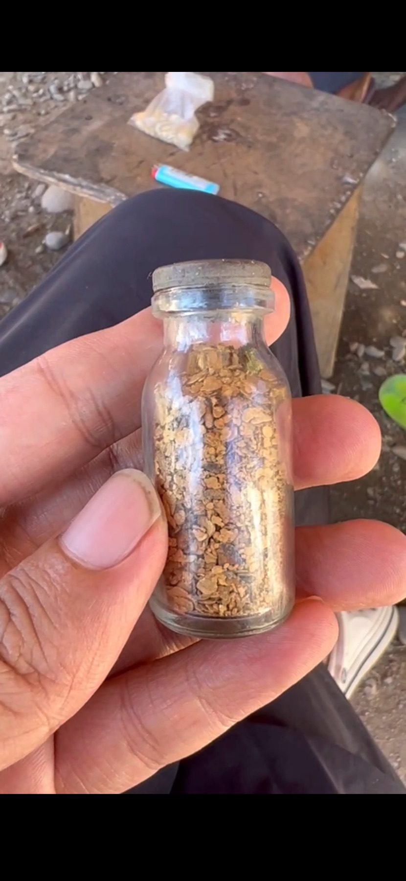 Natural gold flakes collected in a small glass vial